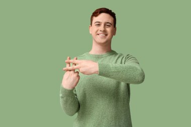 Yakışıklı genç adam yeşil arka planda parmakları olan hashtag işareti yapıyor.
