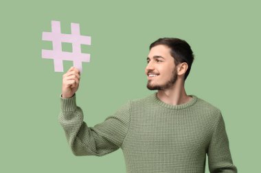 Yeşil arka planda etiket işareti olan mutlu genç adam.