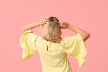 Pembe arka planda kısa saçlı genç bir kadın.