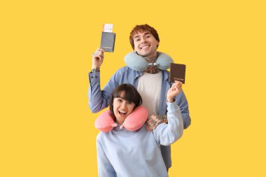 Boyun yastığı ve sarı arka planda pasaportu olan iki genç turist.