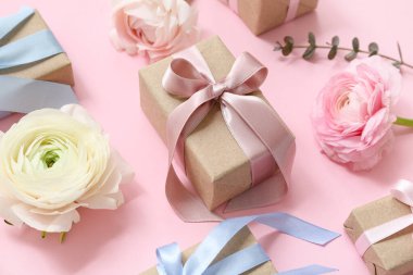 Pembe arka planda güllerle süslü hediye kutuları.