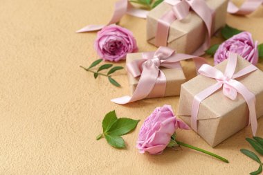 Paketlenmiş kağıt hediye kutuları ve bej arka planda güzel çiçekler.