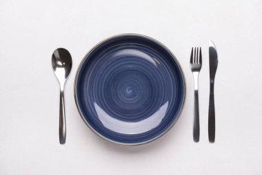 Beyaz zemin üzerinde donanma plakası ve çatal bıçak takımı olan şık masa ayarları