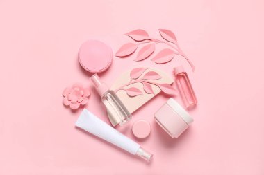 Kağıt çiçekli kozmetik ürünlerin bileşimi ve pembe arka planda yapraklar