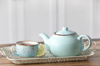 Çaydanlık tepsisi, bir fincan çay ve limon dilimi mutfaktaki ahşap masada.