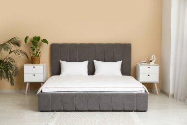 Yeni ortopedik yatak, odada bej duvarın yanındaki şık yatakta battaniyeli.