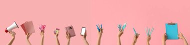 Pembe arka planda okul malzemesi olan bir sürü el.
