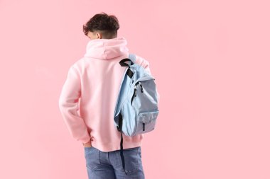 Pembe arka planda sırt çantalı bir erkek öğrenci.