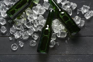 Siyah ahşap arka planda soğuk bira ve buz küpleri.