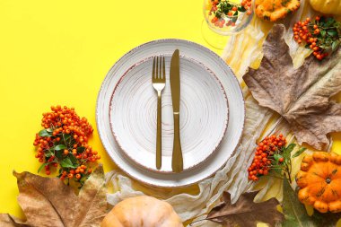 Balkabakları, deniz dikenleri ve sarı arka planda kurumuş yapraklarla sonbahar masası.