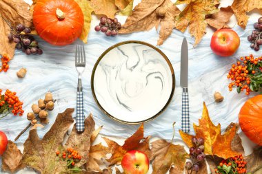 Balkabakları, deniz dikenleri ve beyaz arka planda kurumuş yapraklarla sonbahar masası.