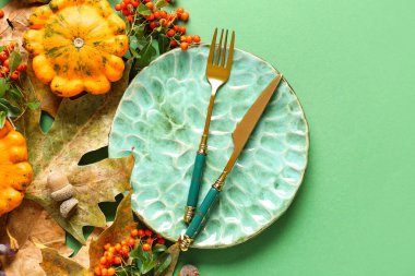 Balkabağı, deniz dikenleri ve yeşil arka planda kurumuş yapraklarla sonbahar sofrası.