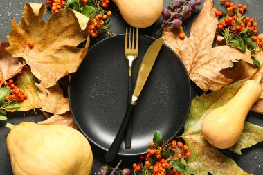 Balkabakları, deniz dikenleri ve siyah arka planda kurumuş yapraklarla sonbahar masası.