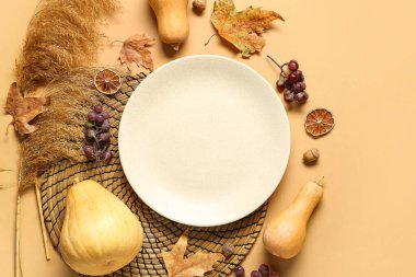 Bej arka planda balkabakları, üzümler ve kuru yapraklarla sonbahar masası ayarı