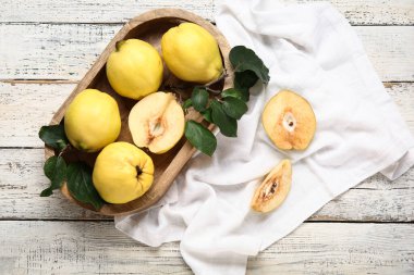 Tatlı olgun ayva tepsileri ve beyaz ahşap arka planda yapraklar