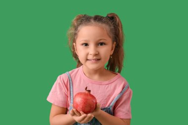 Yeşil arka planda narlı şirin küçük bir kız. Rosh Hashanah (Yahudi Yeni Yılı) kutlaması