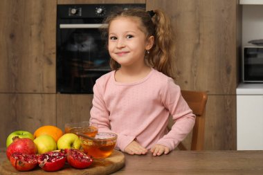 Mutfakta olgun meyveleri ve balı olan tatlı küçük bir kız. Rosh Hashanah (Yahudi Yeni Yılı) kutlaması