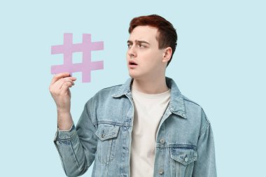 Şok olmuş genç bir adam mavi arka planda etiket işareti ile