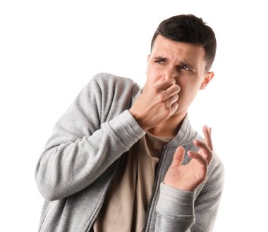 Beyaz arka planda kötü kokan yakışıklı genç adam.