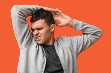 Yakışıklı genç adam turuncu arka planda koltukaltlarından kötü kokular alıyor.