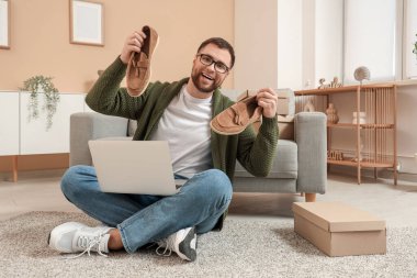 Modern dizüstü bilgisayarı ve şık süet ayakkabıları olan mutlu genç bir adam.