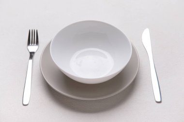 Beyaz arkaplanda temiz tabaklar ve çatal bıçak takımı olan masa ayarları