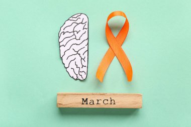 Turuncu kurdeleli kağıt beyin ve turkuaz arka planda marş. Çoklu Skleroz Farkındalık Ayı