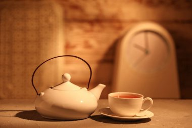 Güzel bir demlik, limon dilimleri ve fincanla ahşap masada bulanık arka planda çay.