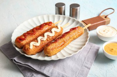 Lezzetli mısırlı sosis ve açık mavi arka planda bir kase sos.