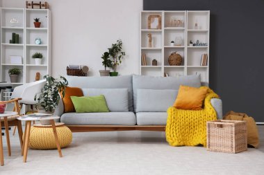 Gri kanepeli ve raf üniteli oturma odasının içi.