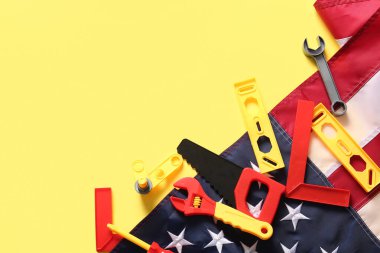 Oyuncak aletler ve sarı arka planda Amerikan bayrağı. İşçi Bayramı kutlamaları