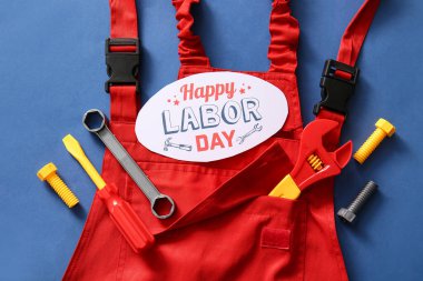 Mesajlı tebrik kartı mutlu LABOR Günü, tulumlar ve mavi arka planda oyuncak aletleri. İşçi Bayramı kutlamaları