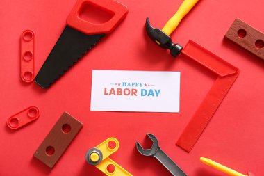 Mesajlı tebrik kartı mutlu LABOR Günü ve kırmızı arka planda oyuncak araçları. İşçi Bayramı kutlamaları