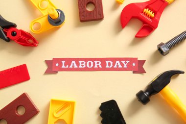 Mesajlı kurdele mutlu LABOR GÜNÜ ve bej arka planda oyuncak araçları. İşçi Bayramı kutlamaları