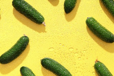 Sarı zemin üzerinde taze yeşil salatalıktan yapılmış bir çerçeve.