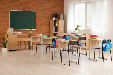 Kara tahta, masa ve sırt çantalı sınıfın içi.