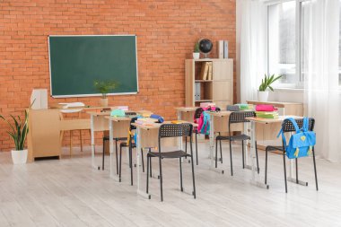 Kara tahta, masa ve sırt çantalı sınıfın içi.