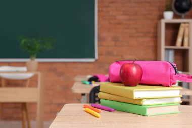Sınıfta masa başında kitap ve elma olan kalem kutusu, yakın plan.