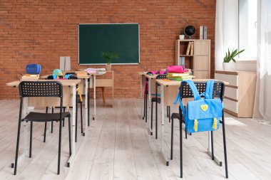 Kara tahta, masa ve sırt çantalı sınıfın içi.