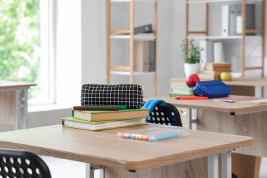 Sınıfta masasında keçeli kalemler ve kitaplar olan kalem kutusu, yakın plan.