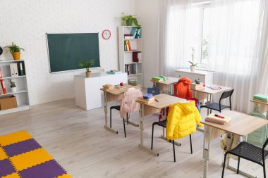 Kara tahtası, masası ve raf ünitesi olan sınıfın içi