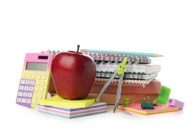 Kırmızı elma ve okul malzemeleri, hesap makinesi ve beyaz arkaplanda bölücüler.