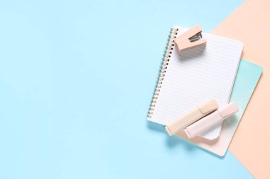 Not defterleri, keçeli kalemler ve renkli arka planda zımba.