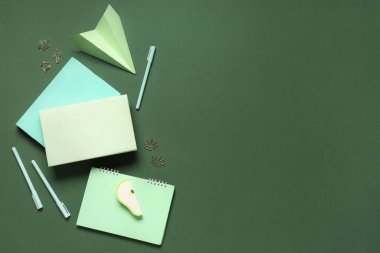 Not defterleri, kağıt uçak ve yeşil arka planda farklı kırtasiye malzemeleri.