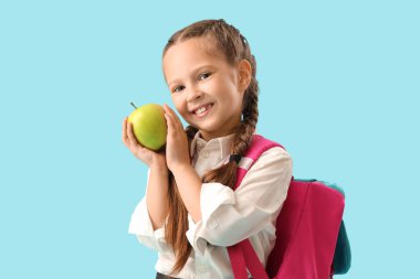Mavi arka planda elma olan küçük okul kızı.