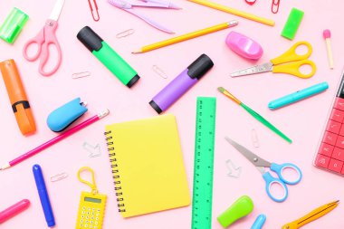 İşaretli okul gereçleri, pembe arka planda defter ve cetvel. Üst görünüm