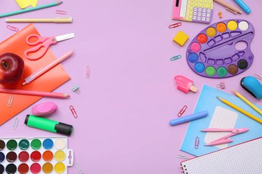 Paletli okul gereçleri, not defterleri ve leylak arkaplanlı kırmızı elma. Üst görünüm