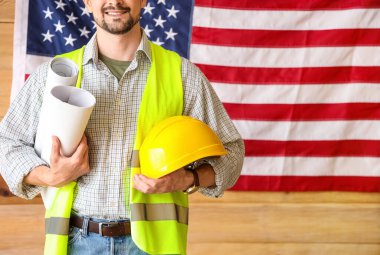 Ev planları ve atölyede Amerikan bayrağına karşı duran erkek mimar. İşçi Bayramı kutlamaları