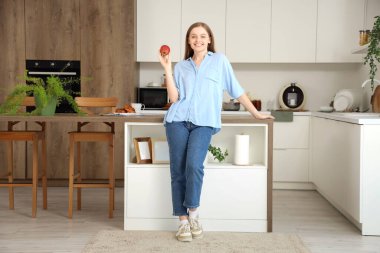 Mutfakta kırmızı elmalı genç bir kadın.