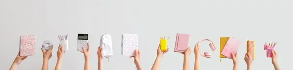 stock image Many hands holding school supplies on light background